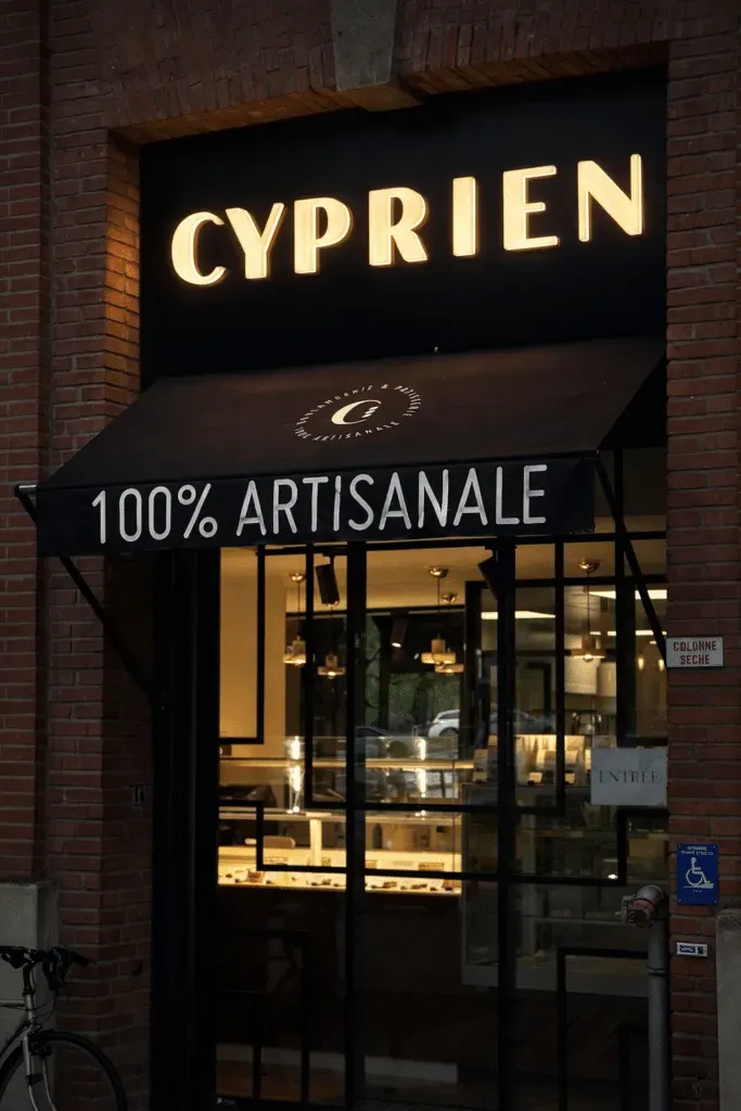Enseigne lumineuse de la boulangerie Cyprien sur façade en brique