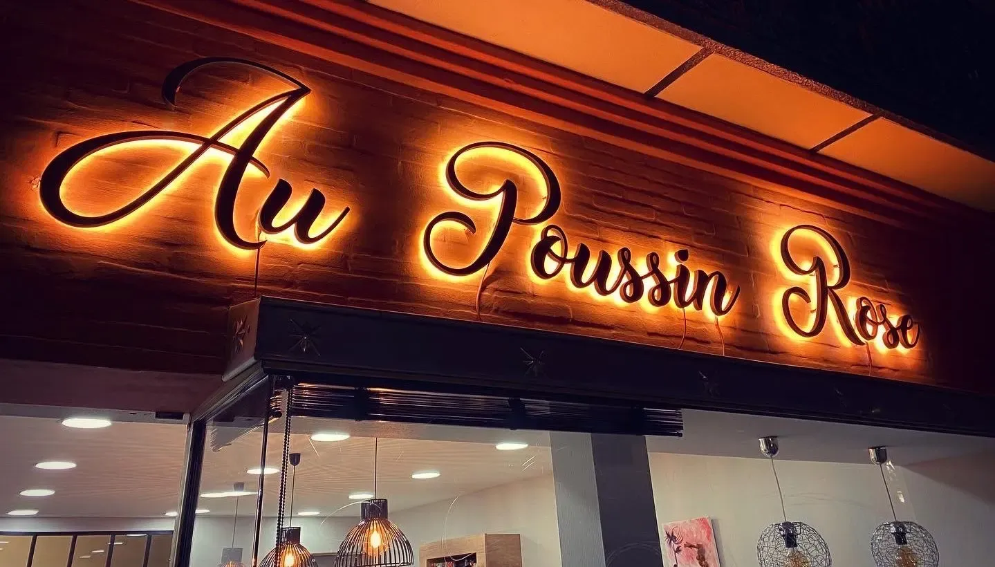 Enseigne rétroéclairée en lettres script du restaurant Au Poussin Rose