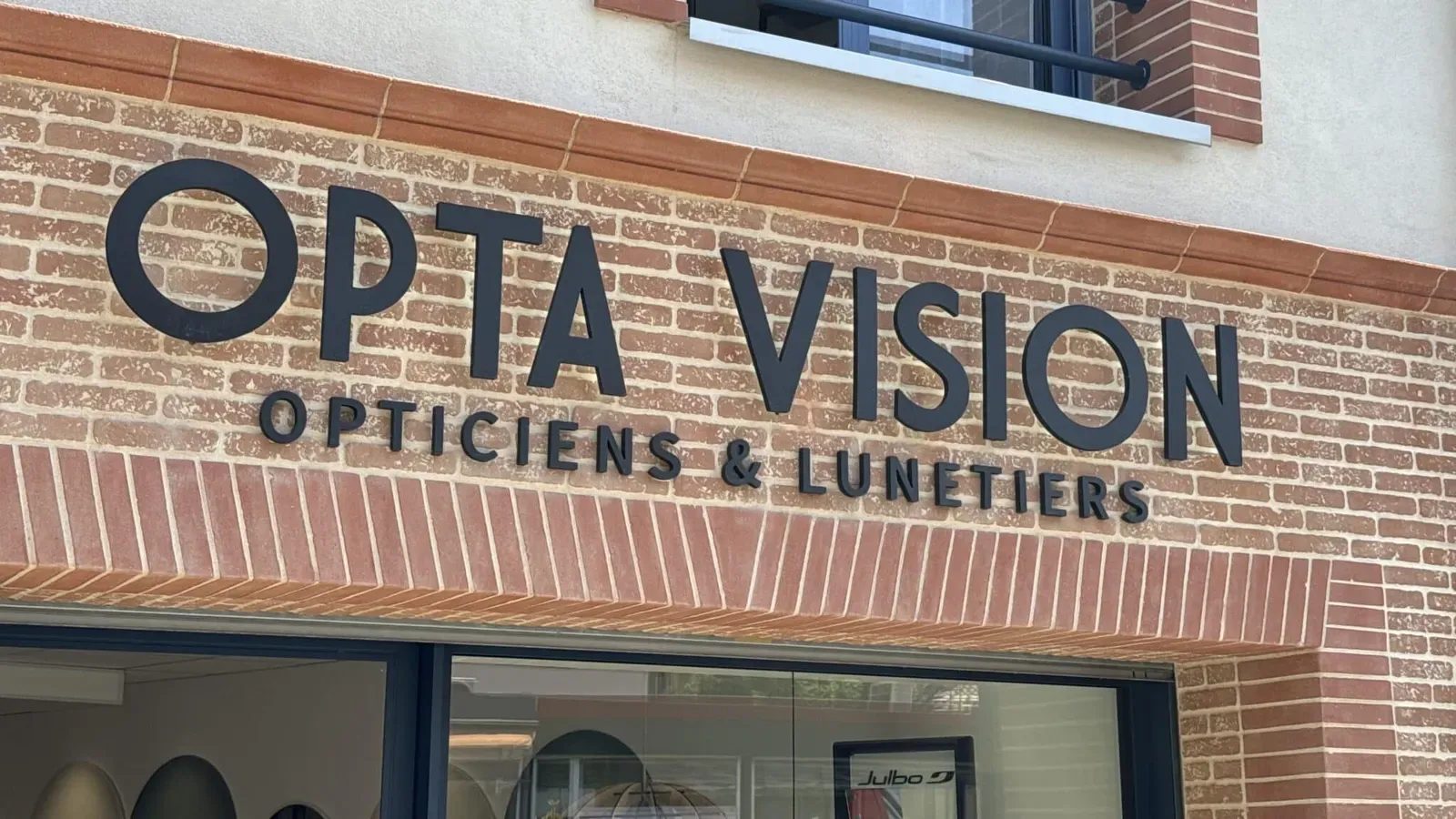 Lettres relief Opta Vision sur une façade en brique