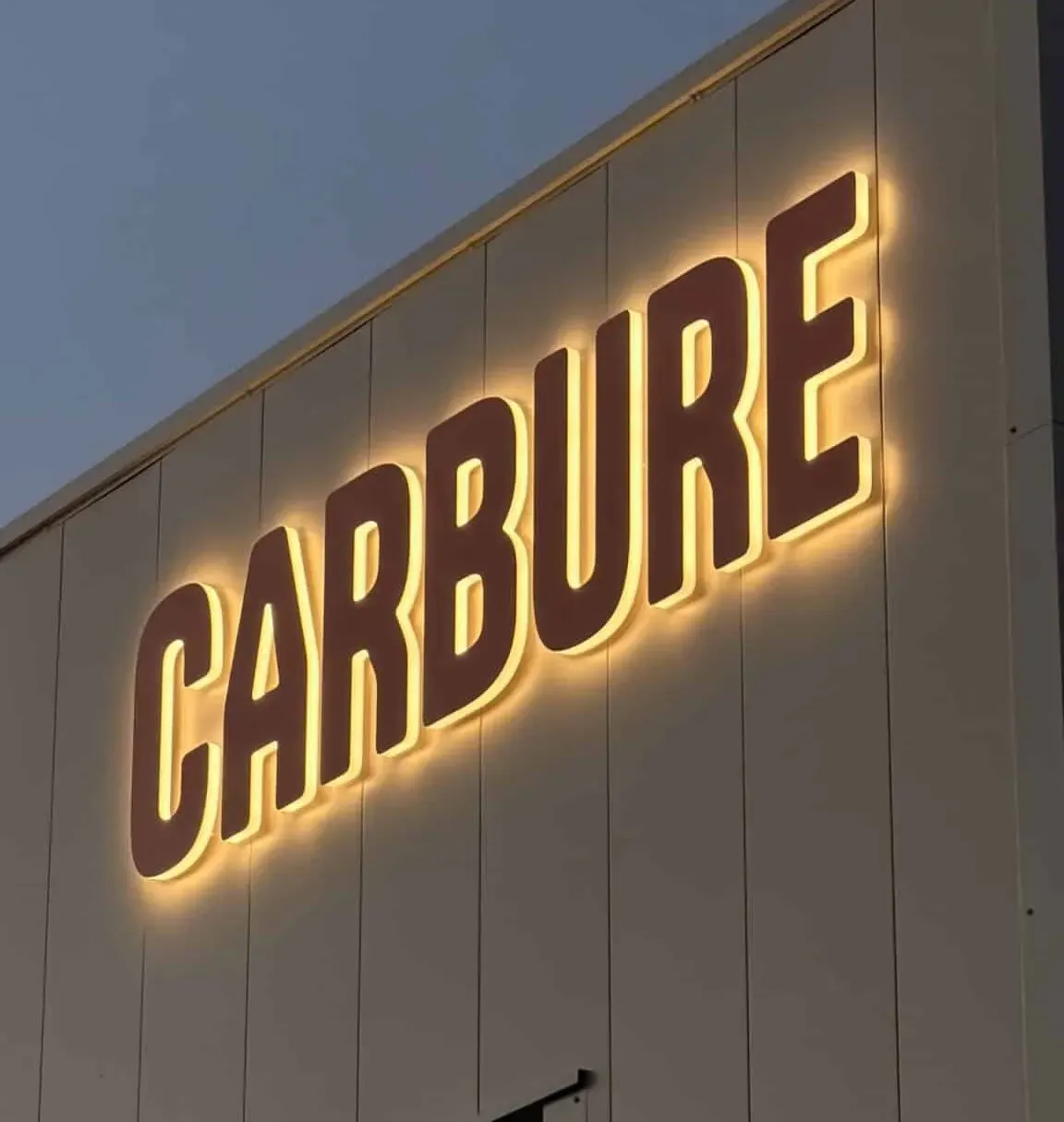 Lettres rétroéclairées Carbure sur un mur clair