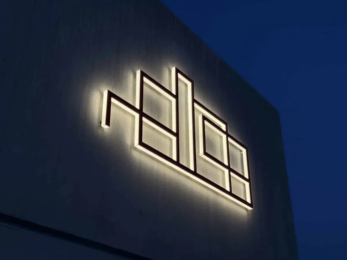 Logo lumineux rétroéclairé sur une façade sombre, la nuit